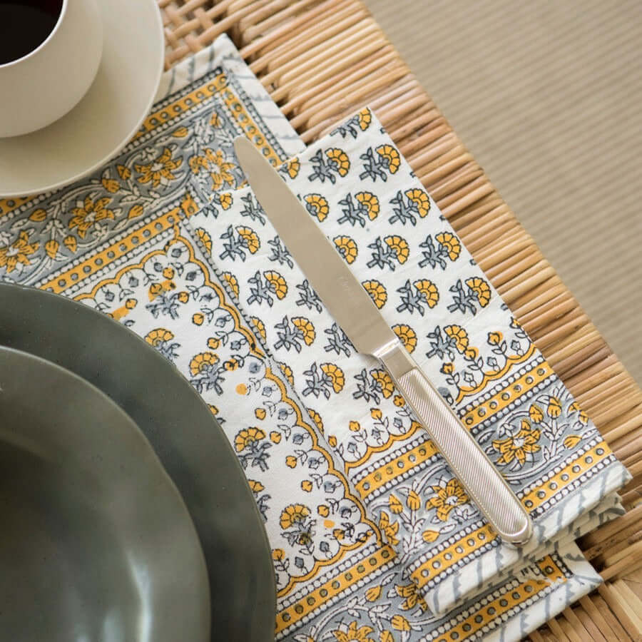 Mantel individual con plato y servilleta de tela Caléndula Ámbar con cubiertos sobre mesa de madera